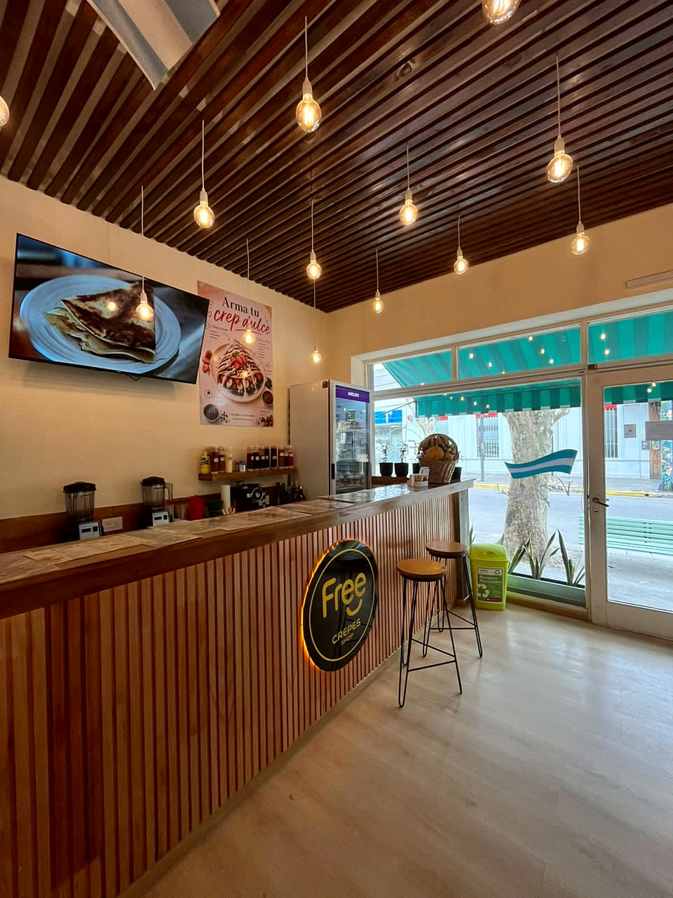 Interior del local con mostrador de madera, crepera y luces colgantes